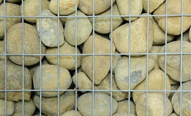 Gabion Baskets Gabion basket filled with stones behind galvanised wire mesh