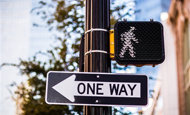 Road Signs & Signage Solutions One-way road sign and pedestrian crossing signal on a street pole