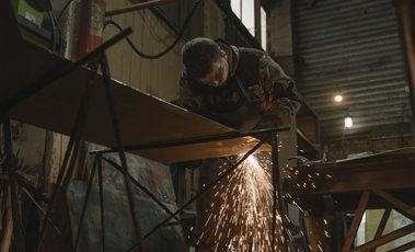 Welder cutting steel with sparks flying in a fabrication workshop